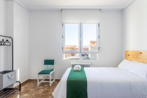a white bedroom with a bed and a chair at Casa Las Rosas in Iniesta