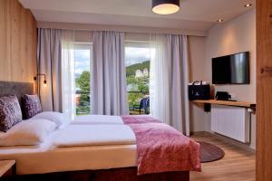 HOTEL SONNBLICK Kaprun Salzburg - incl Zell am See-Kaprun Summercard في كابرون: غرفة فندقية بسرير ونافذة كبيرة