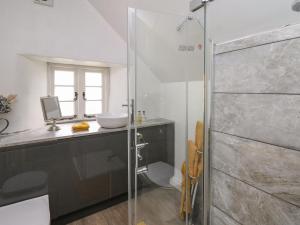a bathroom with a glass shower and a sink at The Bake House in Bridgend