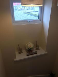 ein Regal mit einer Blume in einer Vase unter einem Fenster in der Unterkunft Helens House Derry City Centre Remarkable 3-Bed in Derry Londonderry