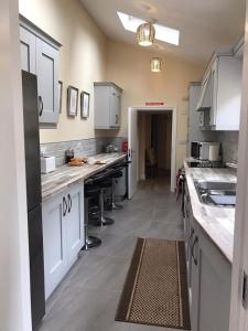 eine Küche mit weißen Schränken und Arbeitsplatten in der Unterkunft Helens House Derry City Centre Remarkable 3-Bed in Derry Londonderry