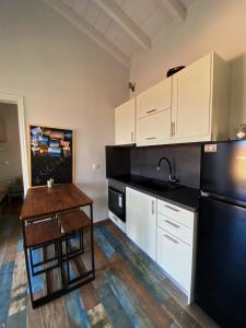 a kitchen with white cabinets and a black refrigerator at The Dona House in Vaia