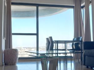 uma mesa de jantar e cadeiras em frente a uma grande janela em דירות נופש מרינה הרצליה em Herzliya B
