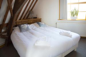 a large white bed in a room with a window at Slapen bij Scherp in Middelburg