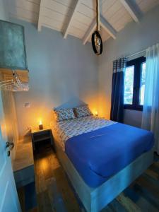 a bedroom with a blue bed and a window at The Dona House in Vaia