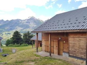 drewniany domek z górami w tle w obiekcie Chalet 6-8 couchages à la Joue du Loup w mieście Dévoluy
