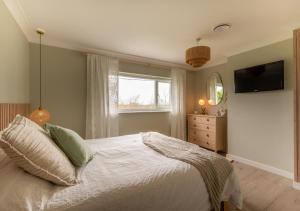 a bedroom with a bed with a television and a window at Highfields - Blythburgh in Blythburgh