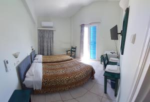 1 dormitorio con 1 cama, 1 silla y 1 ventana en Hellas, en Palaikastro