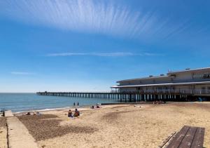 a beach with people sitting on the sand and a pier at Hideout in Felixstowe