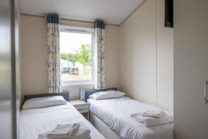 twee bedden in een kleine kamer met een raam bij Bude Holiday Resort in Bude