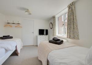 a bedroom with two beds and a window at James Cottage in Southwold