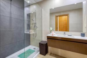 uma casa de banho com um chuveiro e um lavatório. em Rocha Prime Luxury Apartment em Portimão