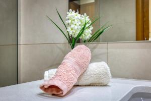uma meia rosa sentada no balcão da casa de banho com um vaso de flores em Rocha Prime Luxury Apartment em Portimão