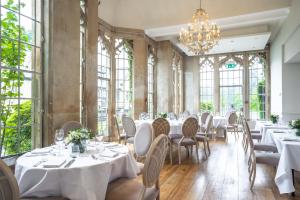 a restaurant with white tables and chairs and windows at Foxhills Club & Resort in Chertsey