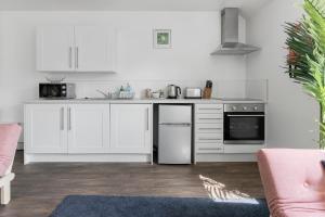 a white kitchen with white cabinets and appliances at Exeter City Centre Apartments Stoop Apartment in Exeter