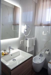 a bathroom with a sink and a toilet and a mirror at LAURIA Luxury Room in Gela