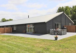a black barn with a patio in a yard at Lavender Cottage in Beccles