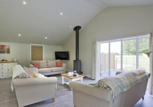 a living room with white furniture and a large window at Lavender Cottage in Beccles