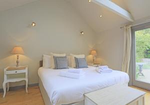 a bedroom with a white bed with towels on it at Little Meadow in Walberswick