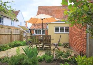 un patio con mesa y sombrilla en Lismore Cottage, en Orford