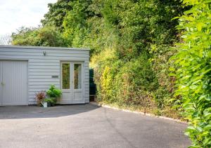 a white garage with a door next to a wall at Little Glebe in Middleton