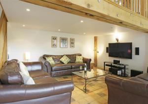 a living room with leather furniture and a flat screen tv at Kings Farm in Wangford