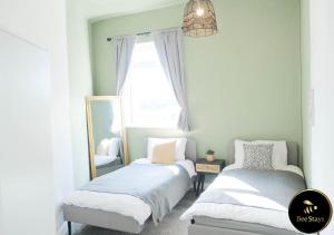 een slaapkamer met 2 bedden en een spiegel bij Bee Stays - Cooper House in Haydock