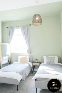 a bedroom with two beds and a chandelier at Bee Stays - Cooper House in Haydock