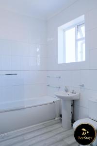 a white bathroom with a sink and a tub and a toilet at Bee Stays - Cooper House in Haydock