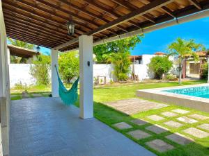 einen Hinterhof mit einer Schaukel und einem Pool in der Unterkunft Casa Cantinho de Arembepe - Linda casa com piscina no litoral norte da Bahia in Camaçari