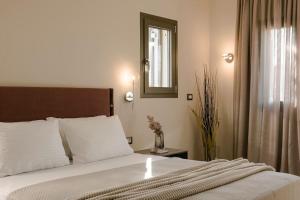 um quarto com uma cama com lençóis brancos e um espelho em Rosairbe Villa Kefalonia em Cefalônia