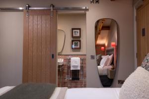 1 dormitorio con puerta, espejo y cama en The Red Lion & Manor House, en Burnsall