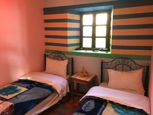 2 camas individuales en una habitación con ventana en Into the Wild HOSTEL en Tacheddirt
