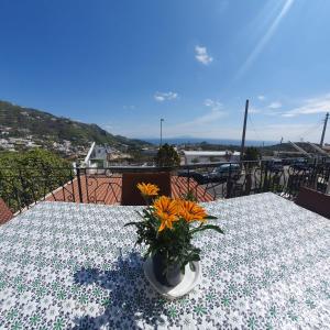 un tavolo con un vaso con dei fiori sopra di Hotel Mareluna Ischia a Ischia