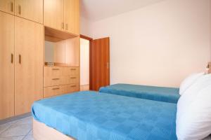 a bedroom with two beds with blue sheets and wooden cabinets at Niko's Central Skala Apartments in Skala Kefalonias