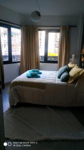 1 dormitorio con cama con almohadas y ventanas en Avellaneda UNO Apartment en Caballito en Buenos Aires