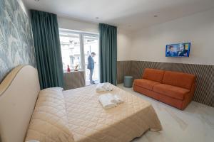 ein Schlafzimmer mit einem Bett und einem orangefarbenen Sofa in der Unterkunft P.C. Boutique H. LifeStyle, Napoli Centro, by ClaPa Group Dislocated Hospitality in Neapel