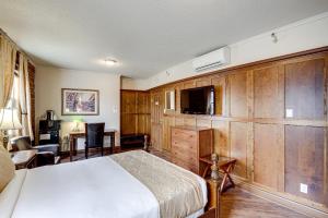 a bedroom with a bed and a tv and a desk at Le Grand Hôtel in Baie-Comeau