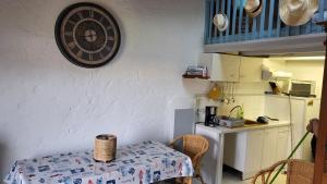 a kitchen with a table and a clock on the wall at Maisonnette Saint-Georges-d'Oléron 17590 à Sauzelle 2 , 3 personnes in Foulerot