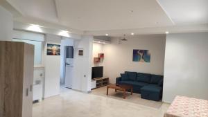 uma sala de estar com um sofá azul e uma televisão em Evelina's studio em Artemida