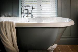 a bath tub with a faucet in a bathroom at The Red Lion & Manor House in Burnsall