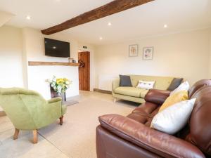 ein Wohnzimmer mit einem Sofa und einem Stuhl in der Unterkunft Tolldish Cottage in Stafford
