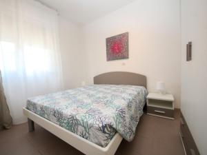 een kleine slaapkamer met een bed, een nachtkastje en een schilderij bij Apartment Veranda by Interhome in Rosapineta