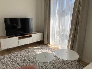 a living room with a television and two white tables at Römerlager in Wasserliesch