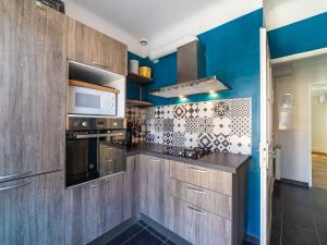 ル・ラヴァンドゥーにあるApartment Boutin by Interhomeの青い壁と木製のキャビネット付きのキッチン