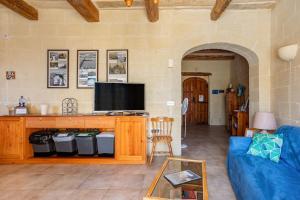uma sala de estar com um sofá azul e uma televisão em Gozo Rustic Farmhouse with stunning views and swimming pool em Sannat