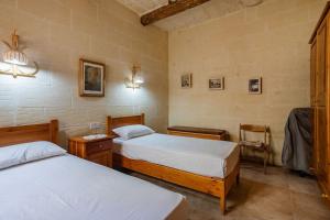 una camera con due letti e una sedia di Gozo Rustic Farmhouse with stunning views and swimming pool a Sannat