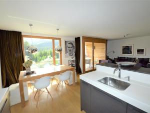 a kitchen with a sink and a table with chairs at Apartment Uehlinger Züger by Interhome in Valbella