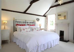 a bedroom with a large white bed and a fireplace at Mill Cottage in Ufford