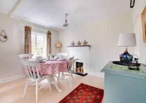 comedor con mesa, sillas y chimenea en Mill Cottage en Ufford